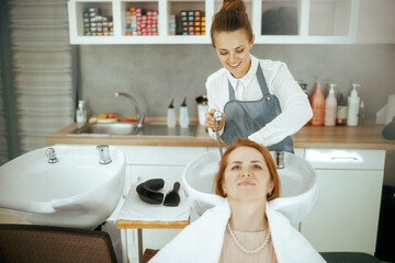 woman hair salon worker in modern hair studio washing hair