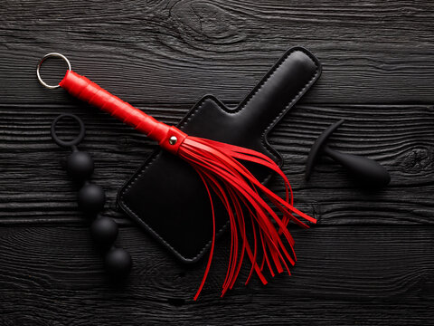 accessories for sex games over black wooden background