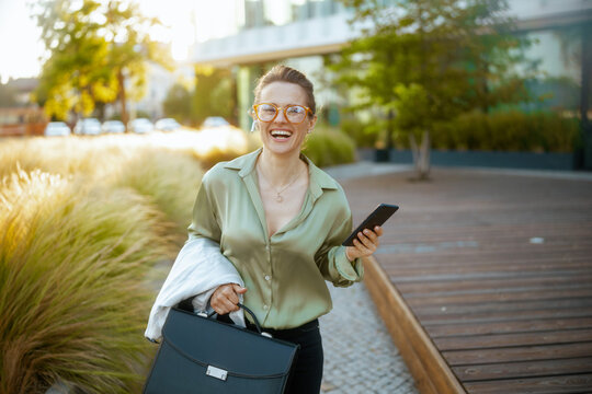 smiling woman employee in green blouse and eyeglasses walking