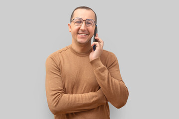 Young man using smartphone, looking at camera on gray background - 761600384