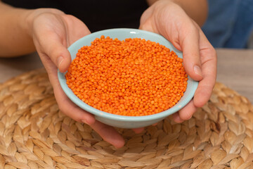 Hands Pouring Red Lentils into Bowl. Hands overflowing with vibrant red lentils over a bowl.