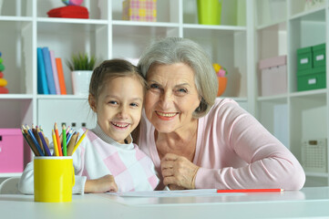 Portrait of grandmother with granddaughter drawing at home 
