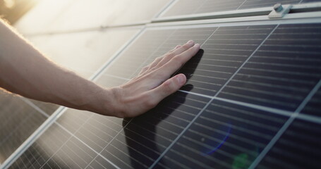 Men's hand strokes the surface of solar panels