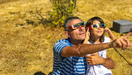 Father and daughter looking at the sun during a solar eclipse on a country park, family outdoor activity - 761614179