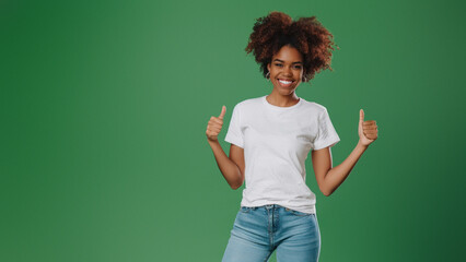 A woman with curly hair and a beaming smile shows thumbs up against a lively green backdrop
