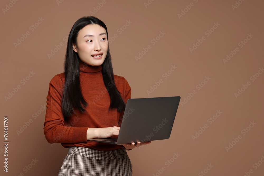 Canvas Prints Portrait of smiling woman with laptop on brown background. Space for text