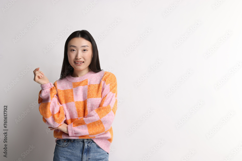 Wall mural Portrait of smiling woman on light background. Space for text