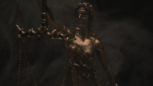 blind libra marble statue rotating in smoky atmosphere on black background with lightning