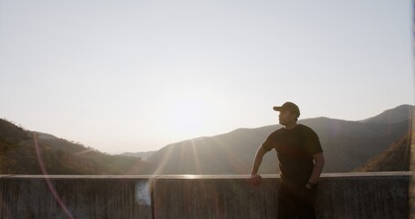 Obraz premium A man stands on a ledge looking out over a mountain range