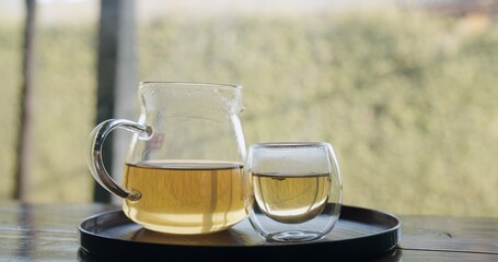 A glass of tea is poured into a glass pitcher