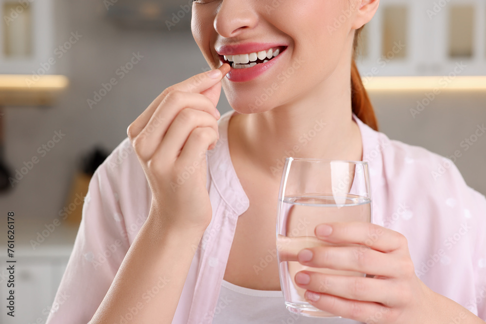 Poster Young woman taking vitamin pill at home, closeup