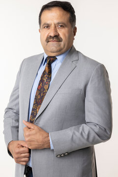 Portrait of confident professional businessman dressed in elegant suit standing against white background