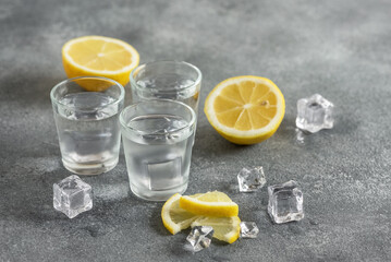 Cold vodka in a shot with ice and lemon, gray concrete background. Side view, selective focus, - 761640793
