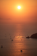 A shot of sunset over caldera in Santorini. Sailboats and catamarans on the water