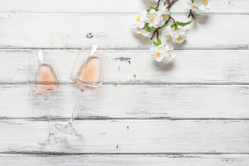 Flat lay two glasses of rose wine and a decorative cherry branch on a white wooden background. Top...