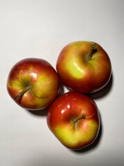 Three red sweet delicious juicy apples lying on a white background