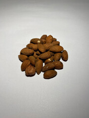 Fototapeta na wymiar A peeled almond nut lies in a pile on a white background