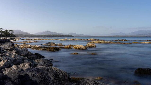 time lapse of a yacht and boat under clouds over mountains over the water in a national park and beautiful rock mountain above the ocean in a national park