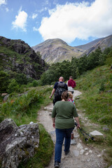 A family walks on the Ben Nevis mountain path leading to Steall waterfall. Scottish highlands on a...