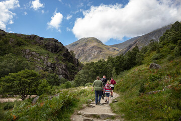 Fototapeta na wymiar A family walks on the Ben Nevis mountain path leading to Steall waterfall. Scottish highlands on a summer day