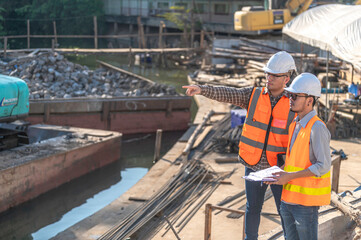 Construction engineer working on a bridge construction site over a river,Civil engineer supervising work,Foreman inspects work at a construction site,Discuss technical problems together