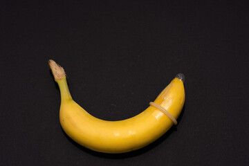 Banana with Condom on black background. Sexual Health and Education Concept
