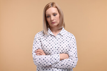 Obraz premium Portrait of sad woman with crossed arms on beige background