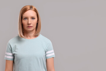 Obraz premium Portrait of sad woman on grey background. Space for text