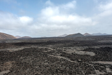 Deserted volcanic landscape with small volcanoes in the distance, Timanfaya National park, Lanzarote, Canary islands