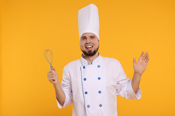 Happy professional confectioner in uniform holding whisk on yellow background