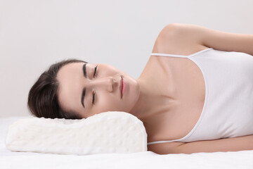 Obraz premium Woman sleeping on orthopedic pillow against light grey background