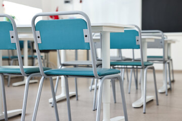 Empty school classroom with desks, blackboard and chairs