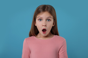 Portrait of surprised girl on light blue background