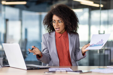 Confused head of department holding sheet with charts and pen in raised hands while looking at pc screen with open mouth. Overwhelmed woman noticing critical mismatch in account of financial report.