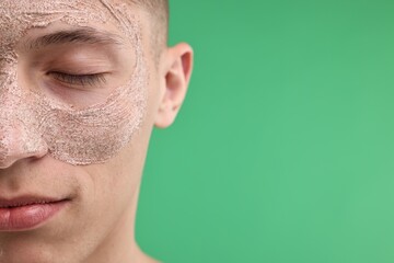 Handsome man with facial mask on his face against green background, closeup. Space for text