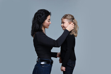 Beautiful mother with little daughter on grey background