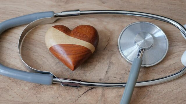 Zoom in shot at wooden heart and medical stethoscope. Heart health concept.