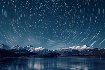 Foto auf Glas Long exposure star tail at night by a lake with snowy mountains in the center in the background © Manzoor