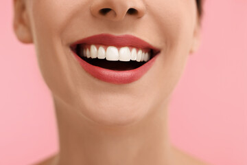 Woman with beautiful lips smiling on pink background, closeup