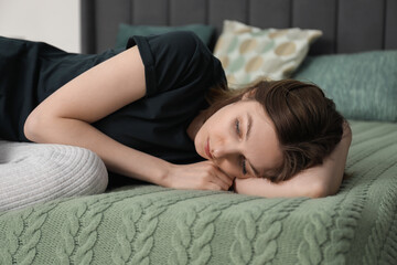 Sad young woman lying on bed at home
