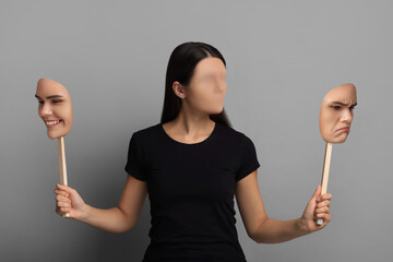 Faceless woman holding her face masks showing different emotions on grey background. Personality...