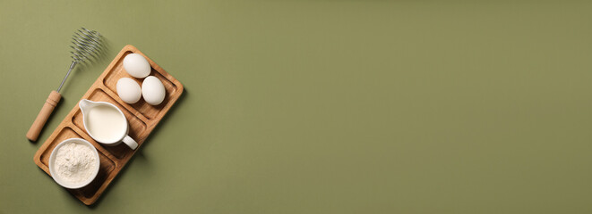 Metal whisk, eggs, milk and flour on khaki background, top view. Banner design with space for text