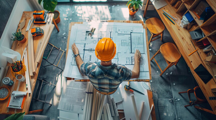 Architect in hard hat examining construction blueprints at a well-organized woodworking workstation.