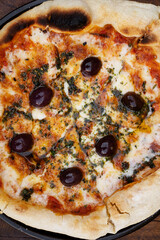 Traditional Italian pizza background. Top view of a mozzarella cheese pizza with tomato sauce, black olives and fresh oregano	