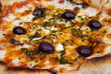 Traditional Italian pizza background. Top view of a mozzarella cheese pizza with tomato sauce, black olives and fresh oregano