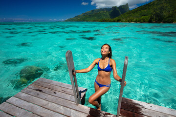 Beach travel vacation woman in hotel villa swimming from ocean deck Tahiti French Polynesia. This...