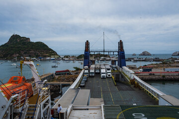 Big transportation trucks park at cargo ship in Baja California Mexico marine dock with industrial...