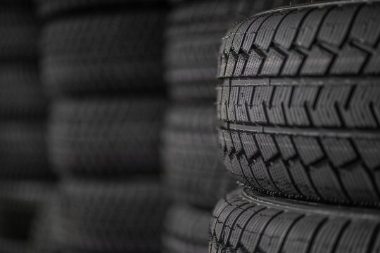 Close-up of rubber tires for the summer or winter season of different thicknesses and diameters on racks in a warehouse of a shop, the store or in the workshop