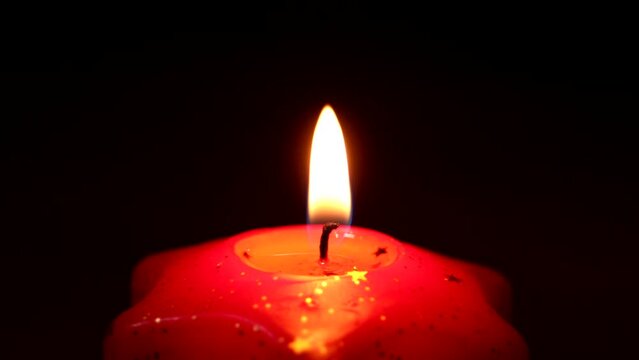 candele rosse su sfondo nero accese con fiamme oro e gialle che evocano un'atmosfera incantevole suggestiva religiosa e natalizia quasi mistica