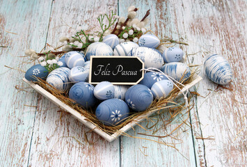 Tarjeta de Pascua Felices Pascuas. Huevos de Pascua azules en un nido con el texto Felices Pascuas.